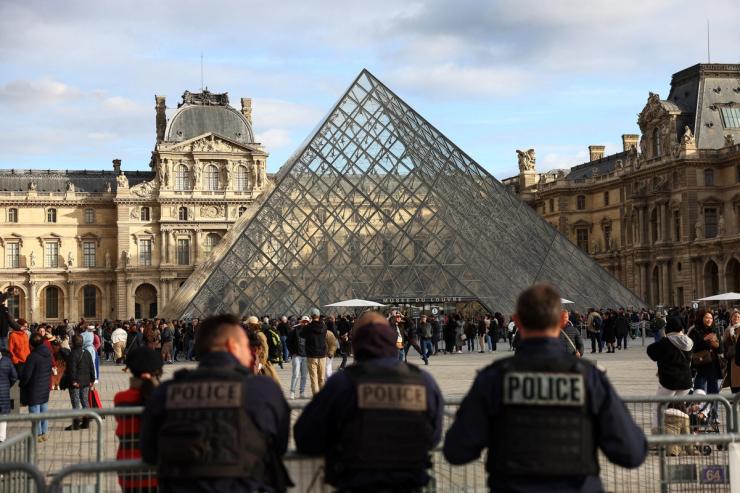 Police officers stand guard near the Louvre Pyramid