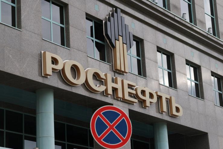 The company’s logo adorns the facade of an office building of Rosneft, one of Russia’s major oil producers, as a road sign stands on a street in Moscow.