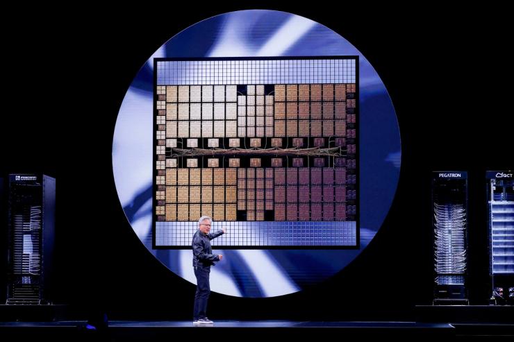 Nvidia CEO Jensen Huang points to a giant semiconductor graphic during a visual presentation.