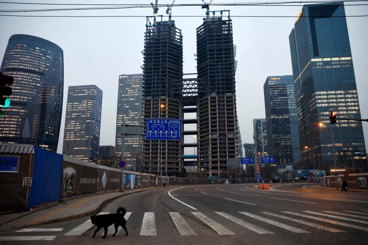 A dog crosses a road at a financial district with buildings under construction.