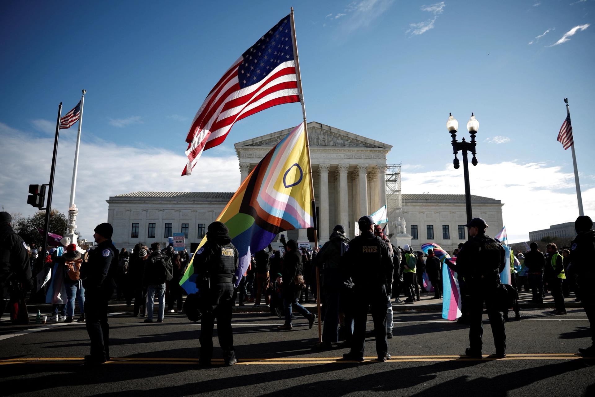 People hold flags and signs as the U.S. Supreme Court hears arguments over an appeal by U.S. President Joe Biden’s administration of a lower court’s decision upholding a Republican-backed ban in Tennessee on gender-affirming medical care for transgender minors, outside the court in Washington, U.S., December 4, 2024.