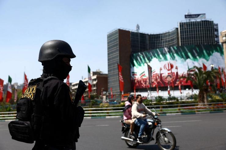 A member of a police force stands guard on a street, amid the U.S.-Israeli conflict with Iran, in Tehran