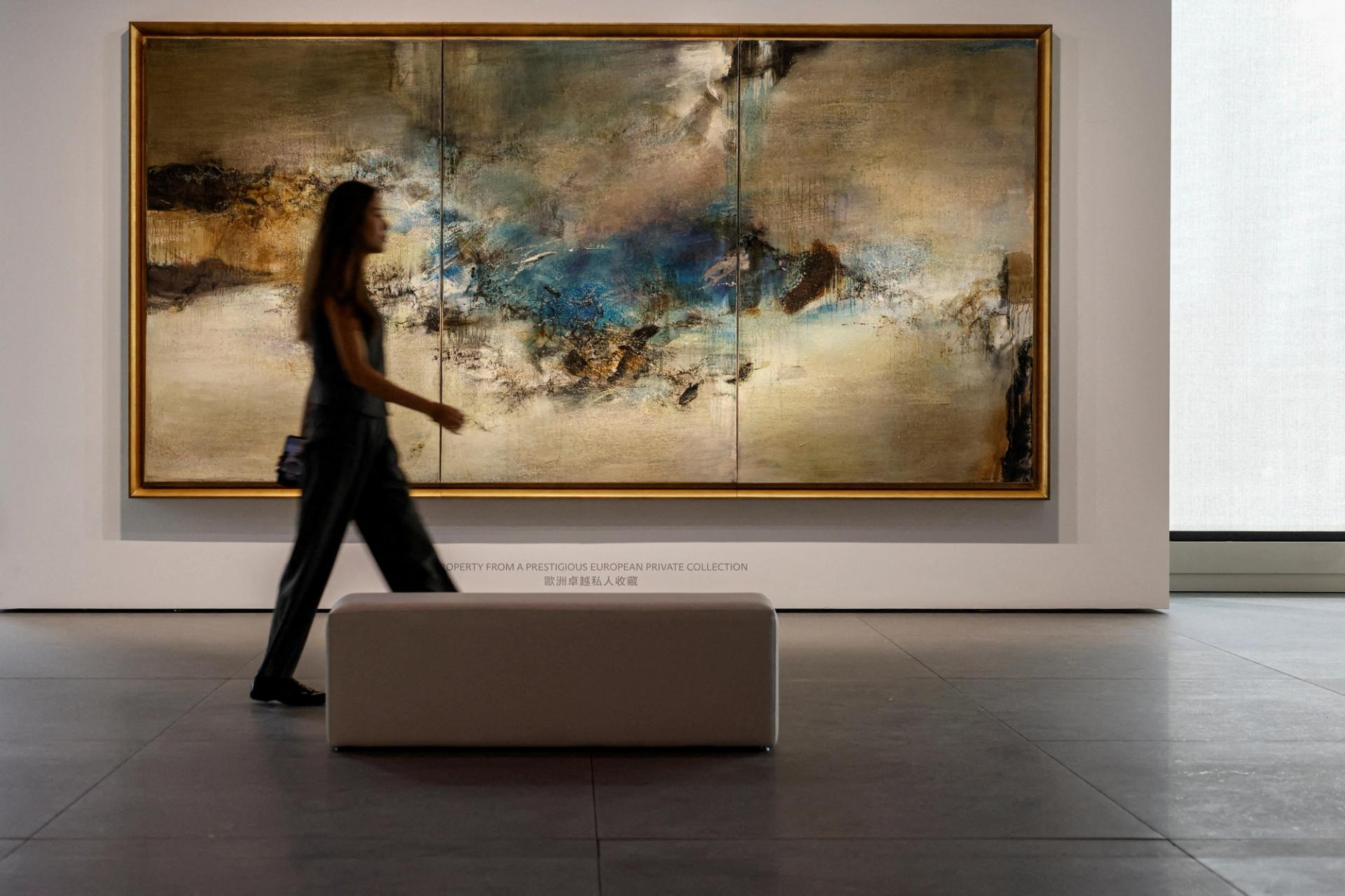 An employee poses for a photo in front of “05.06.80-Triptyque” by artist Zao Wou-Ki during the inaugural sale at Christie’s new Asia Pacific headquarters in Hong Kong