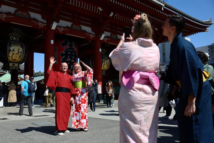 Foreign tourists wearing Japanese traditional kimono clothes pose for a photograph near Sensoji temple at Asakusa district
