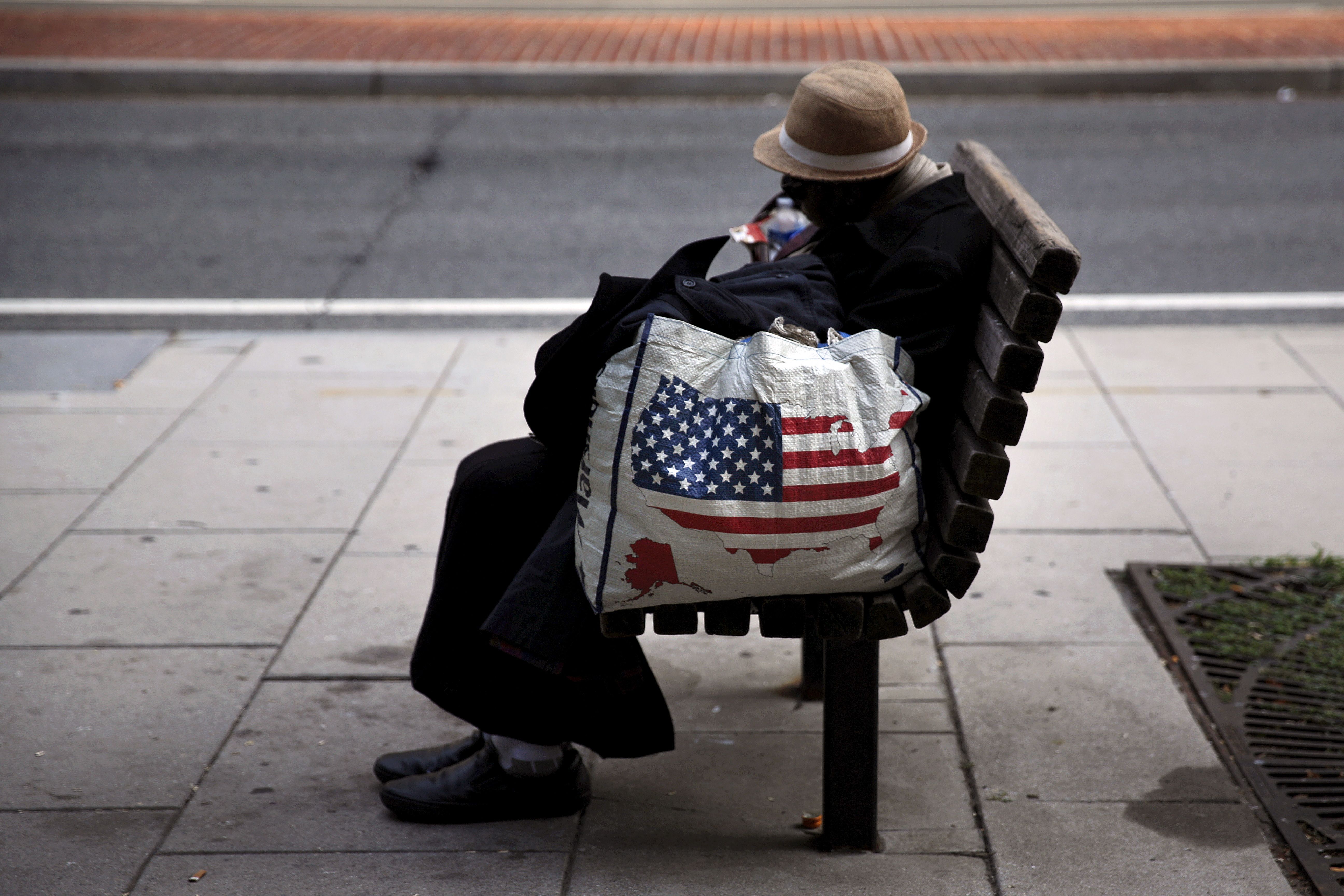 A homeless woman sits on a bench few blocks away from the White House in downtown Washington