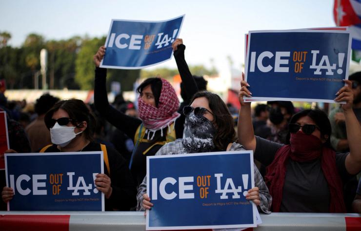 Protesters hold placards as they gather around the Los Angeles Federal Building following multiple detentions by Immigration and Customs Enforcement.