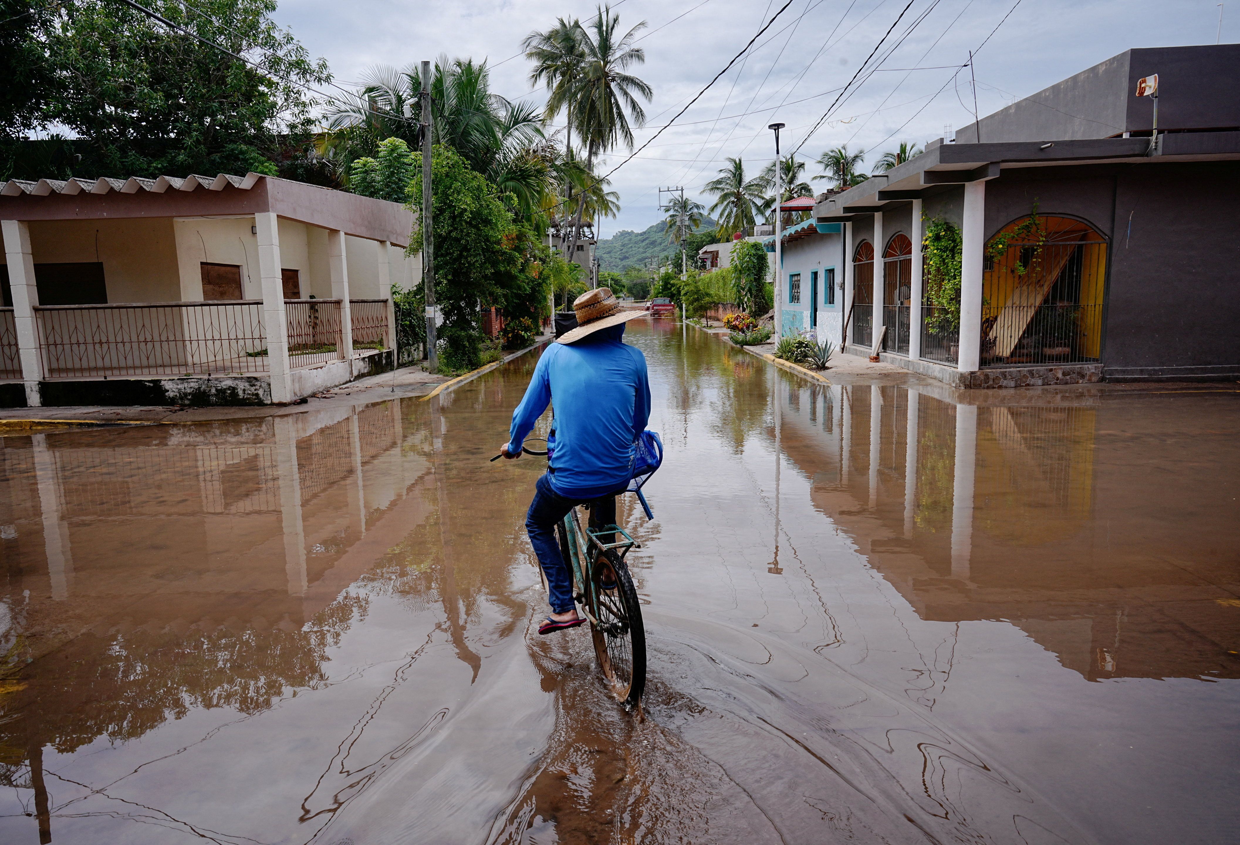 A person rides a bicycle through a flooded street in Mexico. 