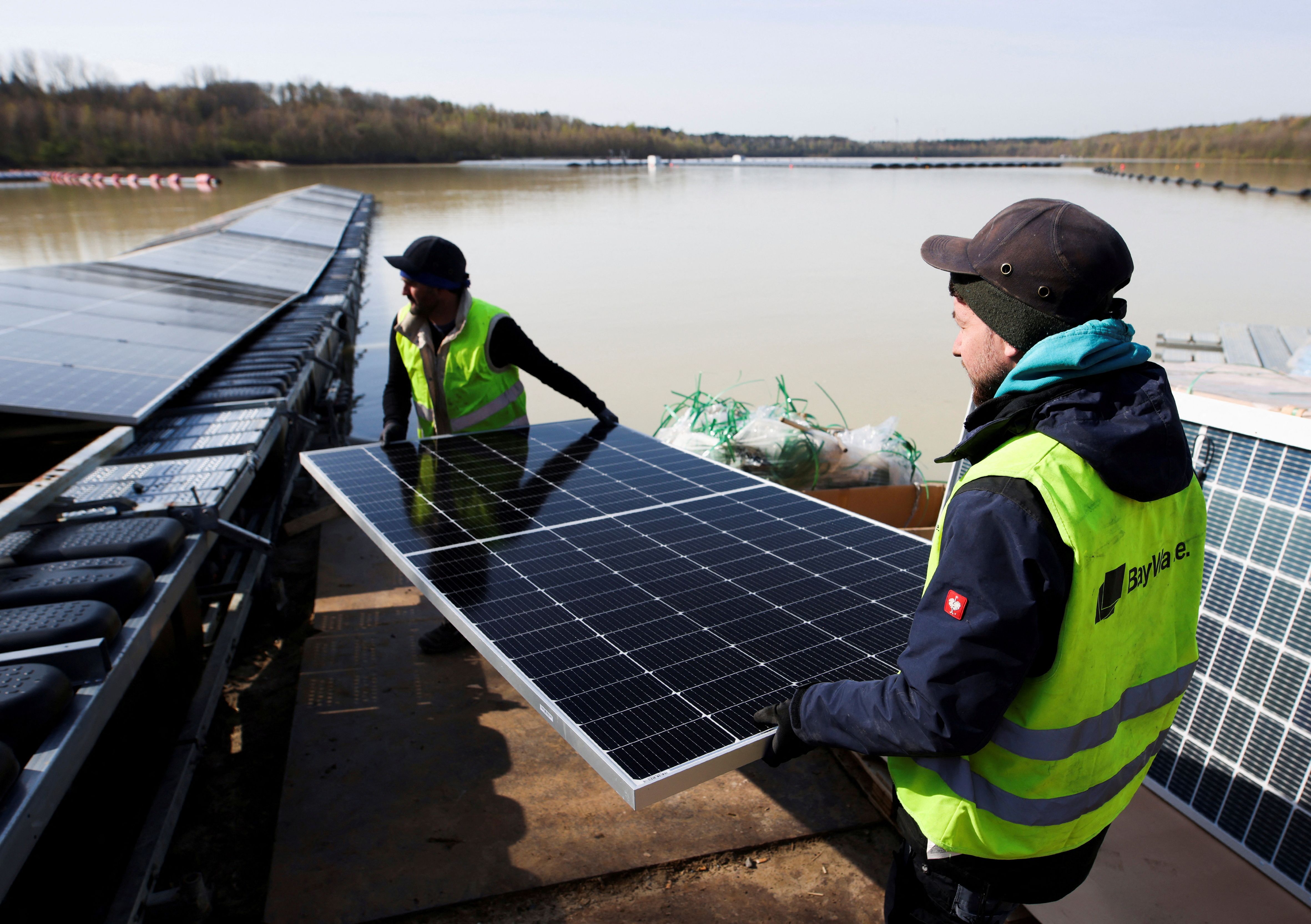 Workers install solar panels on a floating photovoltaic power plant on lake Silbersee (Lake Silver) in Haltern am See, Germany