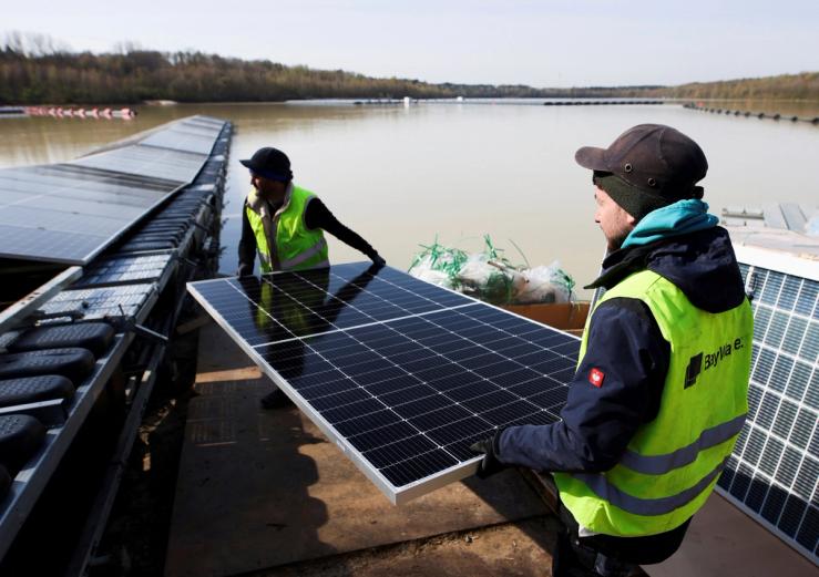 Workers install solar panels on a floating photovoltaic power plant on lake Silbersee (Lake Silver) in Haltern am See, Germany