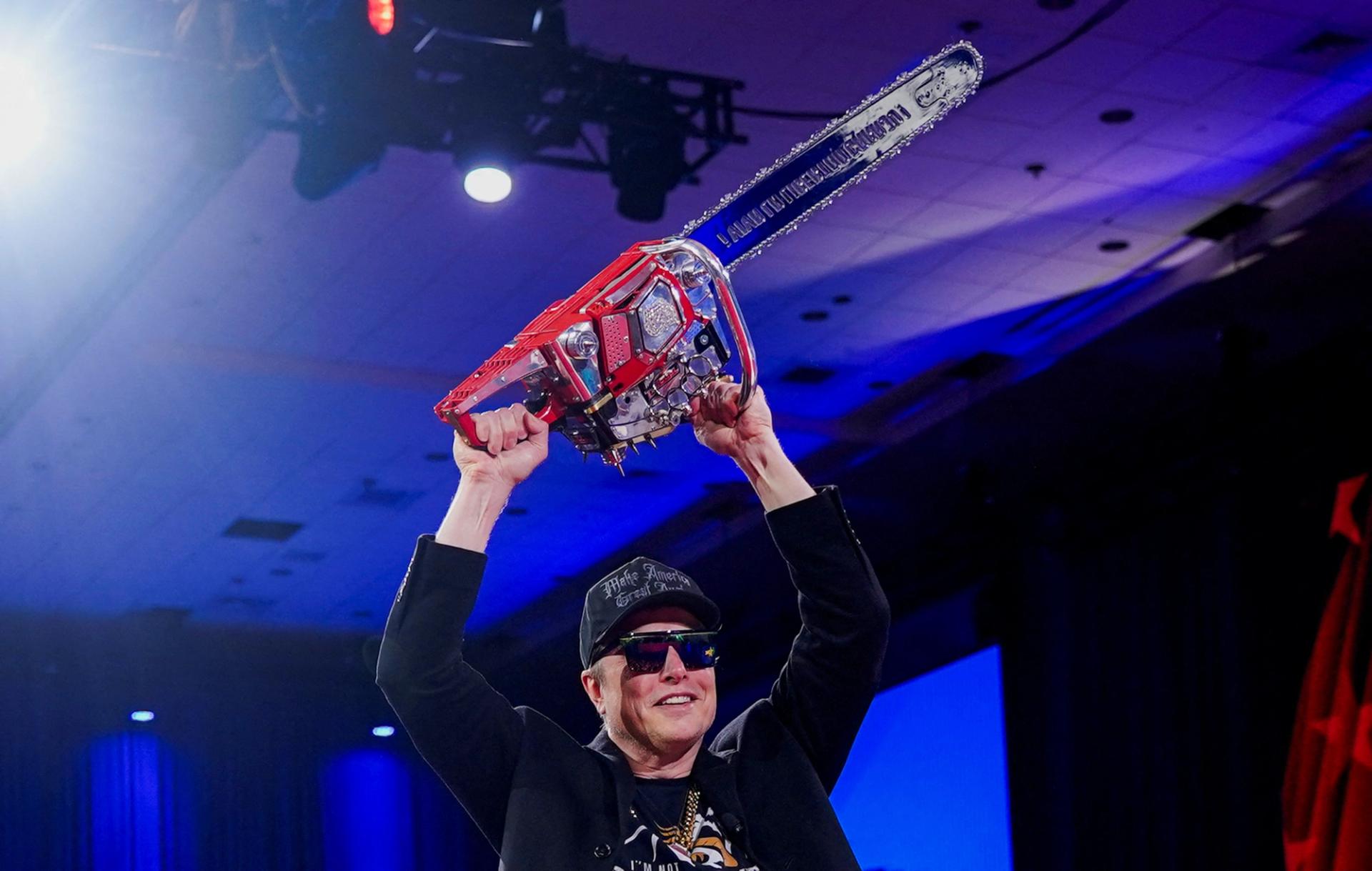 Elon Musk holds a chainsaw onstage as he attends the Conservative Political Action Conference (CPAC).