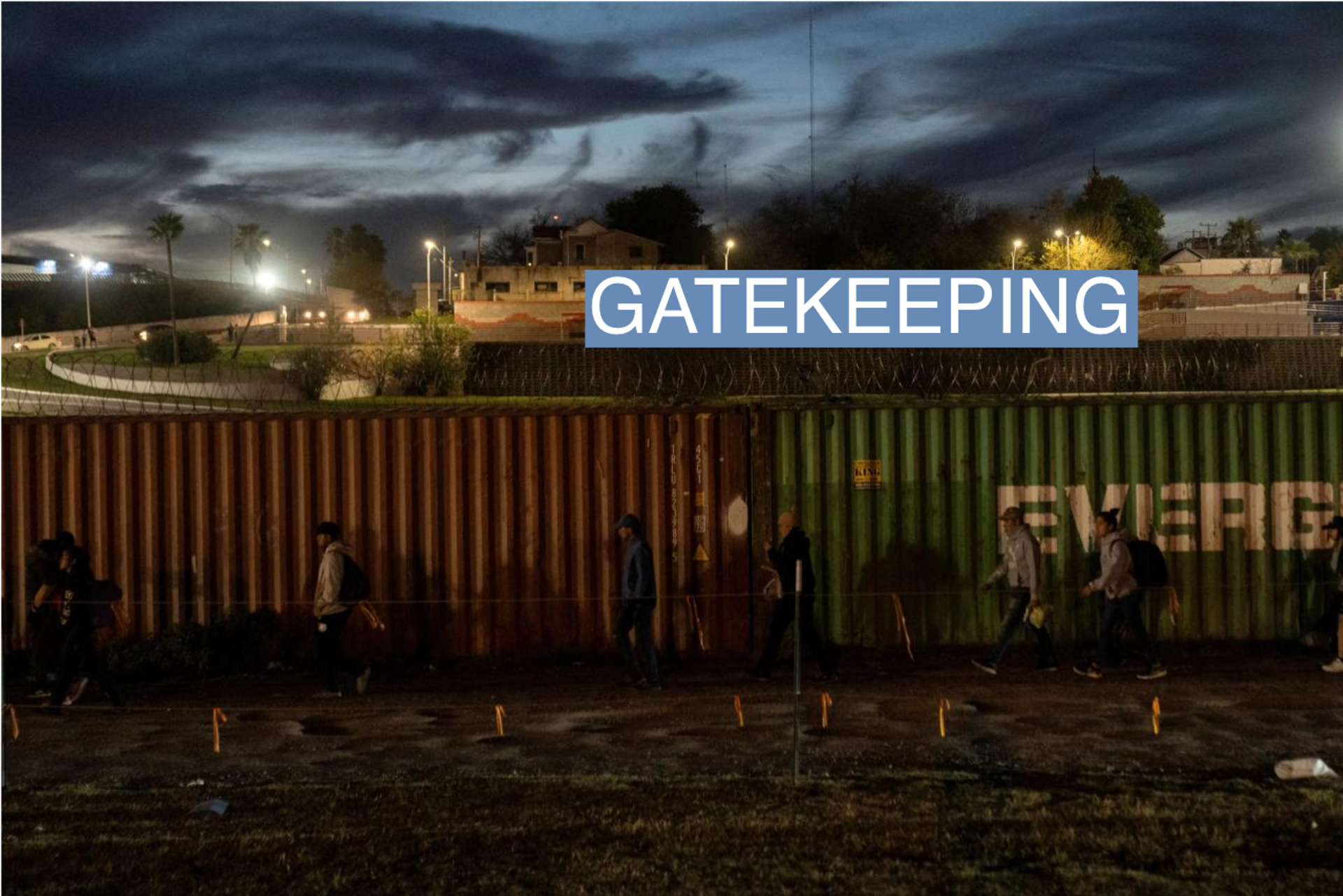 Migrants walk along a barricade of shipping containers after crossing from Mexico into Eagle Pass, Texas, U.S., December 19, 2023. REUTERS/Cheney Orr