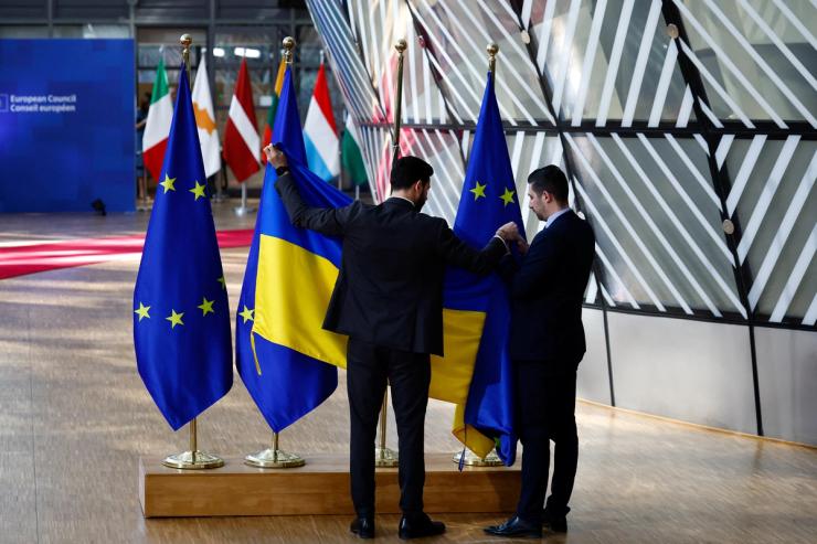 Ushers replace an EU flag with a Ukrainian flag on the day of the European Unit summit in Brussels.
