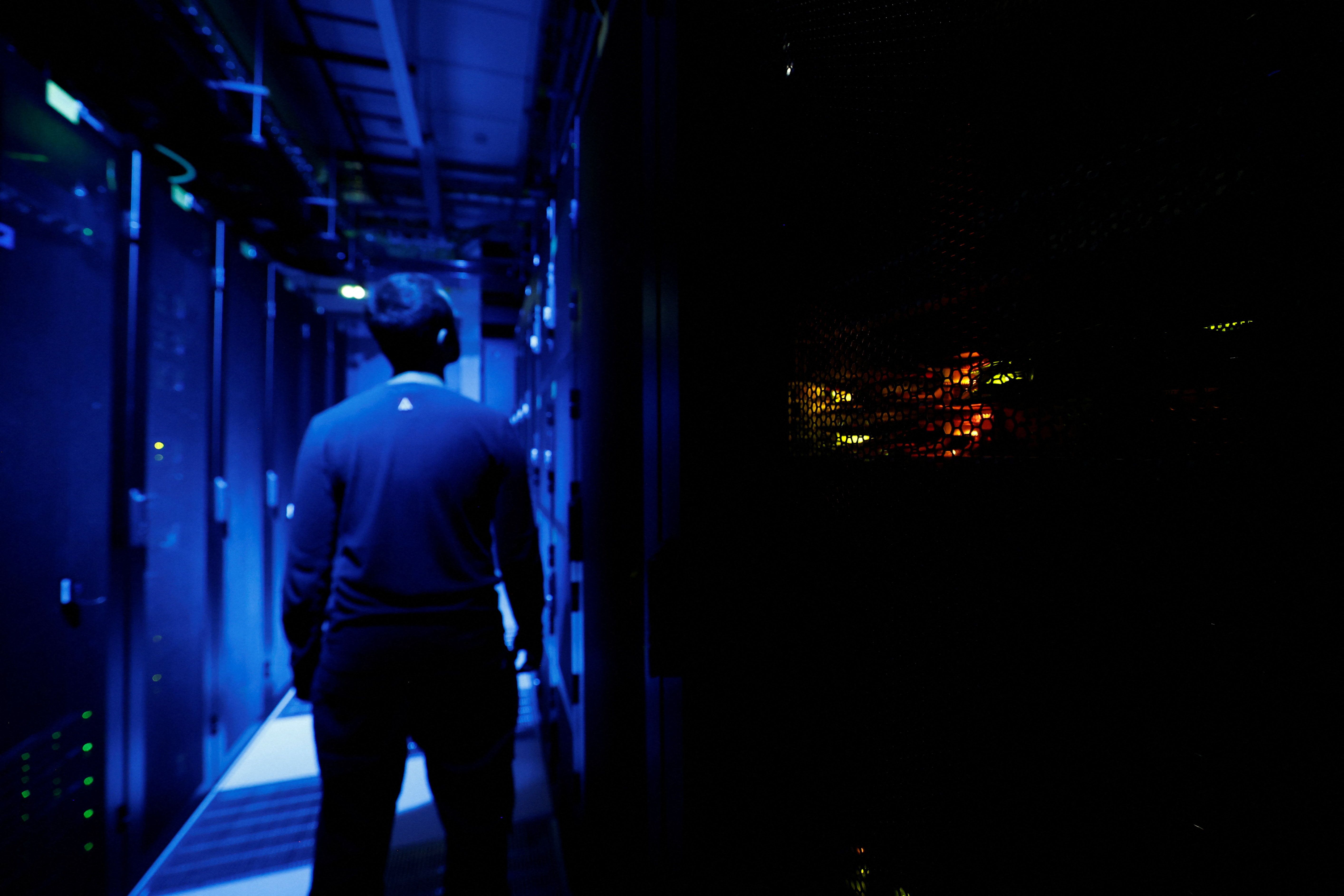 An employee inside a darkly lit data center