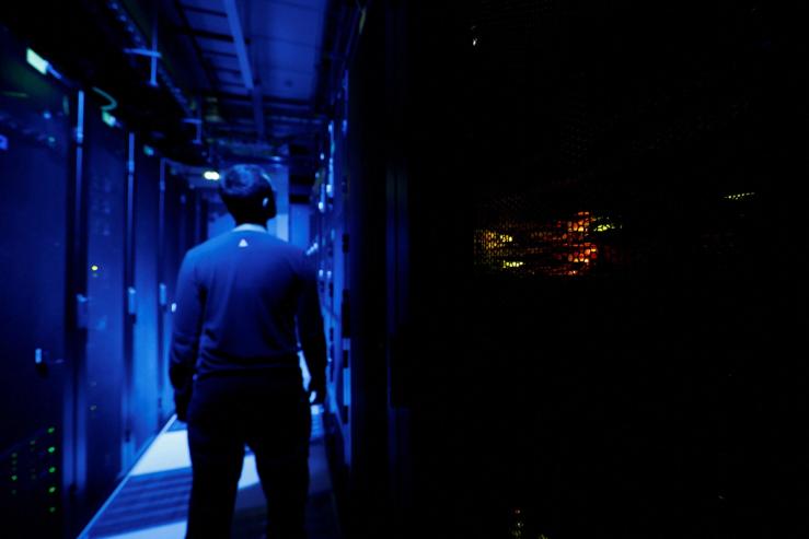 An employee inside a darkly lit data center