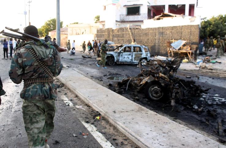 A soldier patrols near the wreckage of a suicide car bomb blast in Somalia.