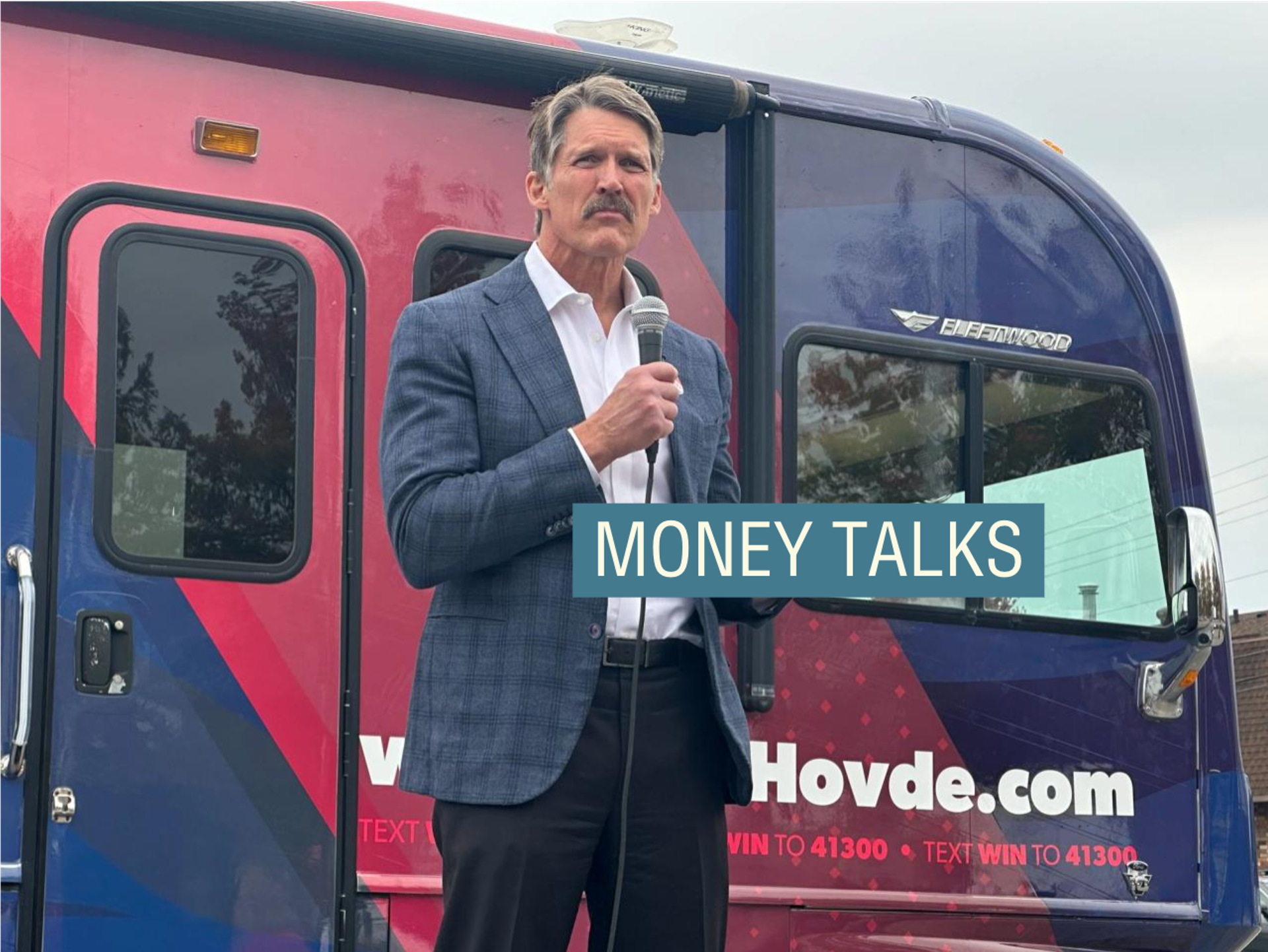 Eric Hovde, wearing a check blazer and white shirt, delivers a speech in Wisconsin