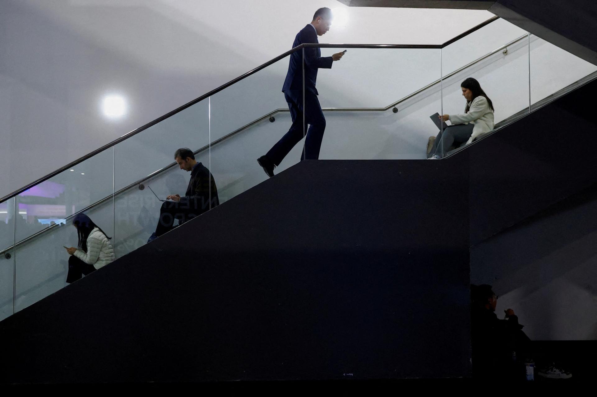 Visitors check their computers and mobile phones during the Mobile World Congress trade show, in Barcelona.