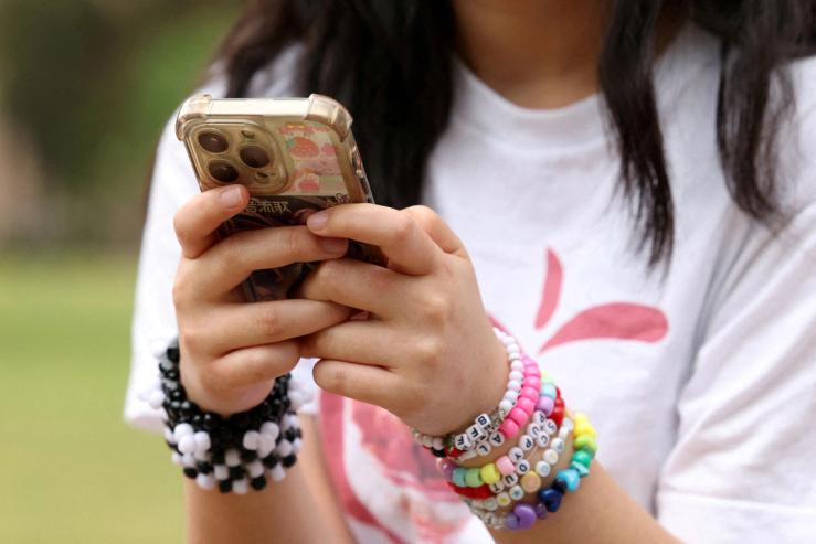 A girl poses holding her phone after an interview discussing Australia’s social media ban for users under 16