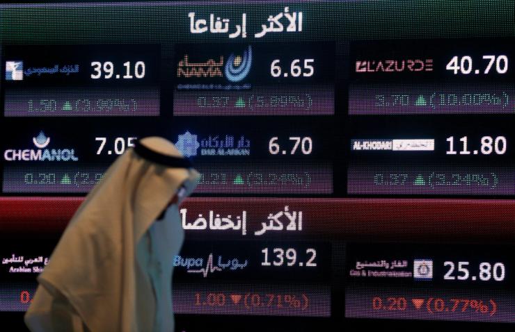 An investor walks past a screen displaying stock information at the Saudi Stock Exchange (Tadawul) in Riyadh.