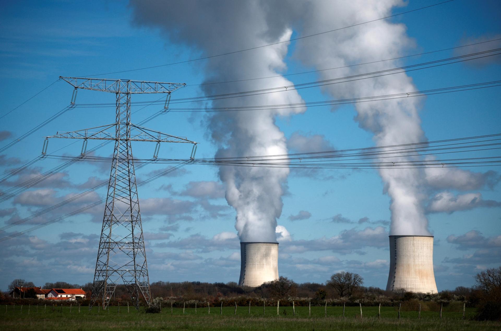 An electrical power pylon of high-tension electricity power lines is pictured as steam rises from cooling towers of a nuclear power station in Civaux, France, 2024.