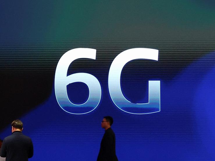 People walk past a 6G logo.