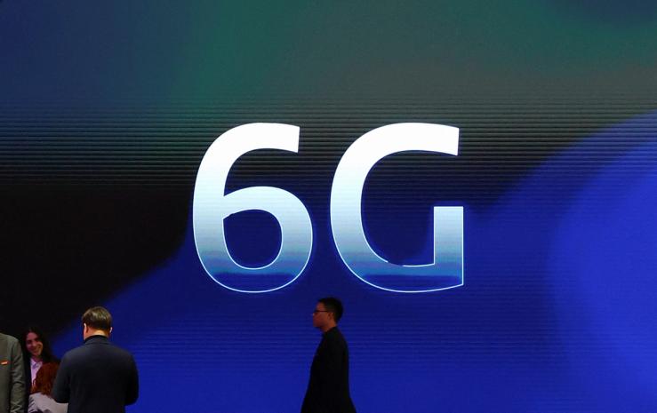 People walk past a 6G logo.