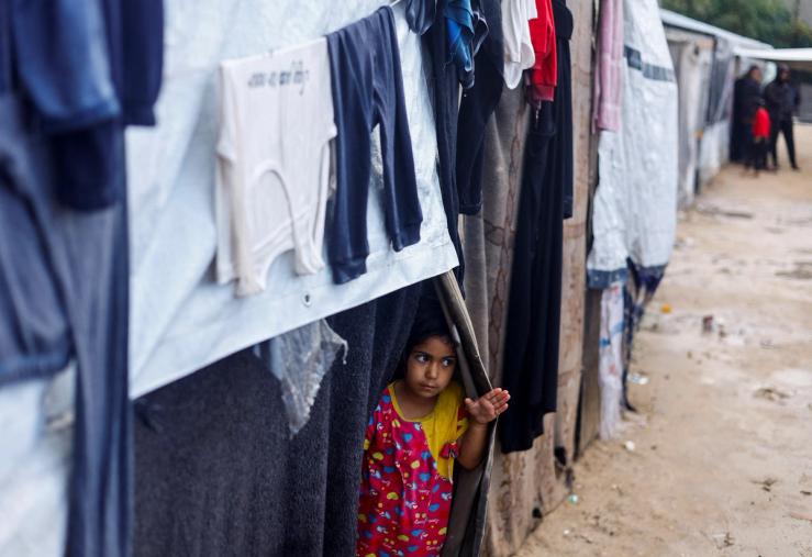A displaced Palestinian girl looks out of a tent on a rainy day, amid the ongoing conflict between Israel and Hamas, in Rafah, in the southern Gaza Strip May 6, 2024.