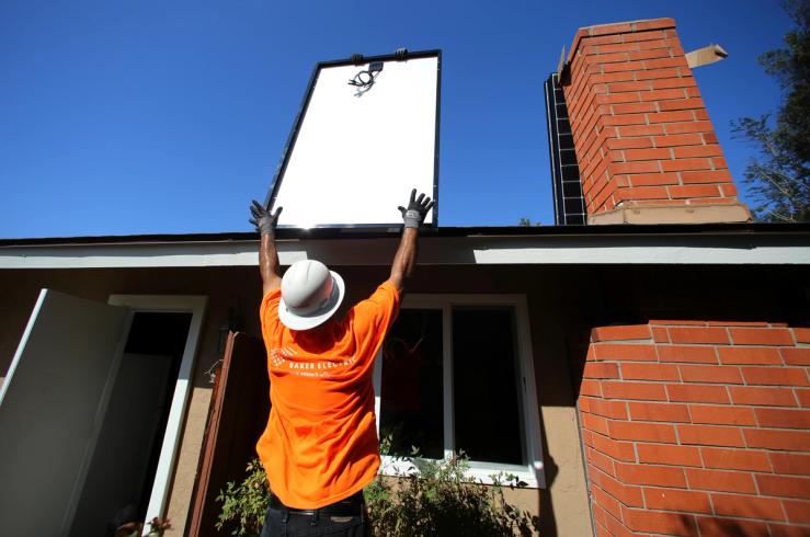 Workers lift a solar panel onto a roof during a residential solar installation in Scripps Ranch, San Diego, California.