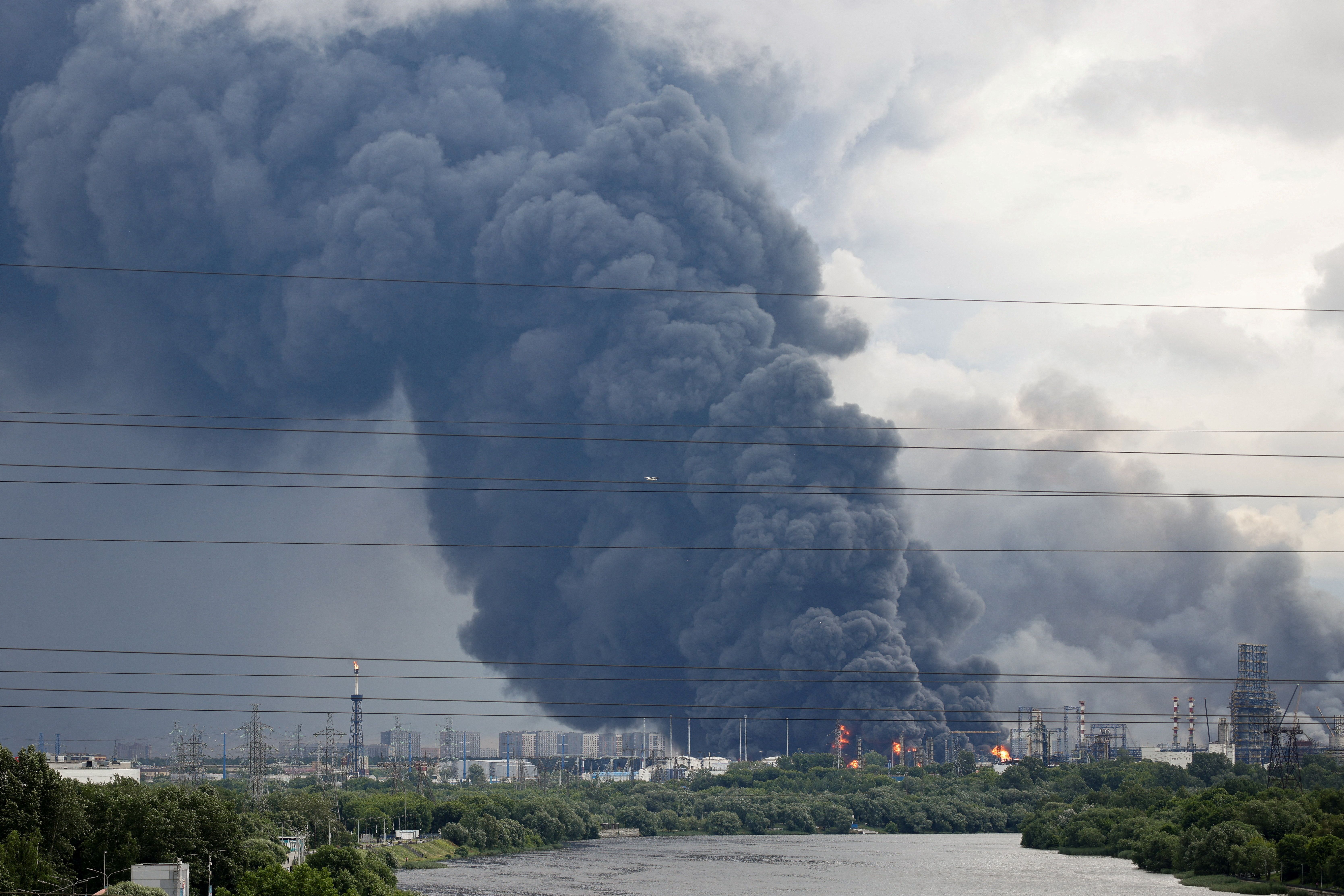 Thick plumes of smoke with flames rise from an oil refinery following a Ukrainian drone attack.