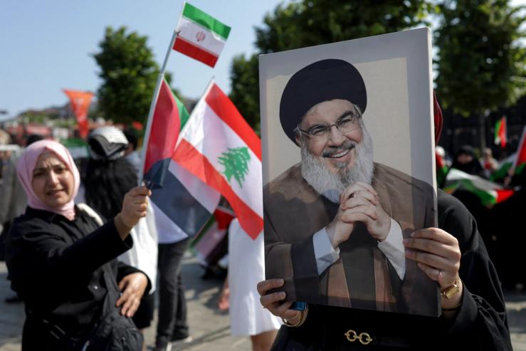 A person holding a photo of Hezbollah’s former leader.