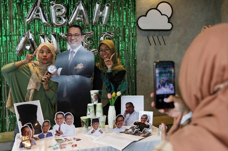 Women pose for a photograph with a cutout depicting Presidential candidate Anies Baswedan during the Humanies Cup Sleeve Event at the Kopi Nako cafe in Jakarta.