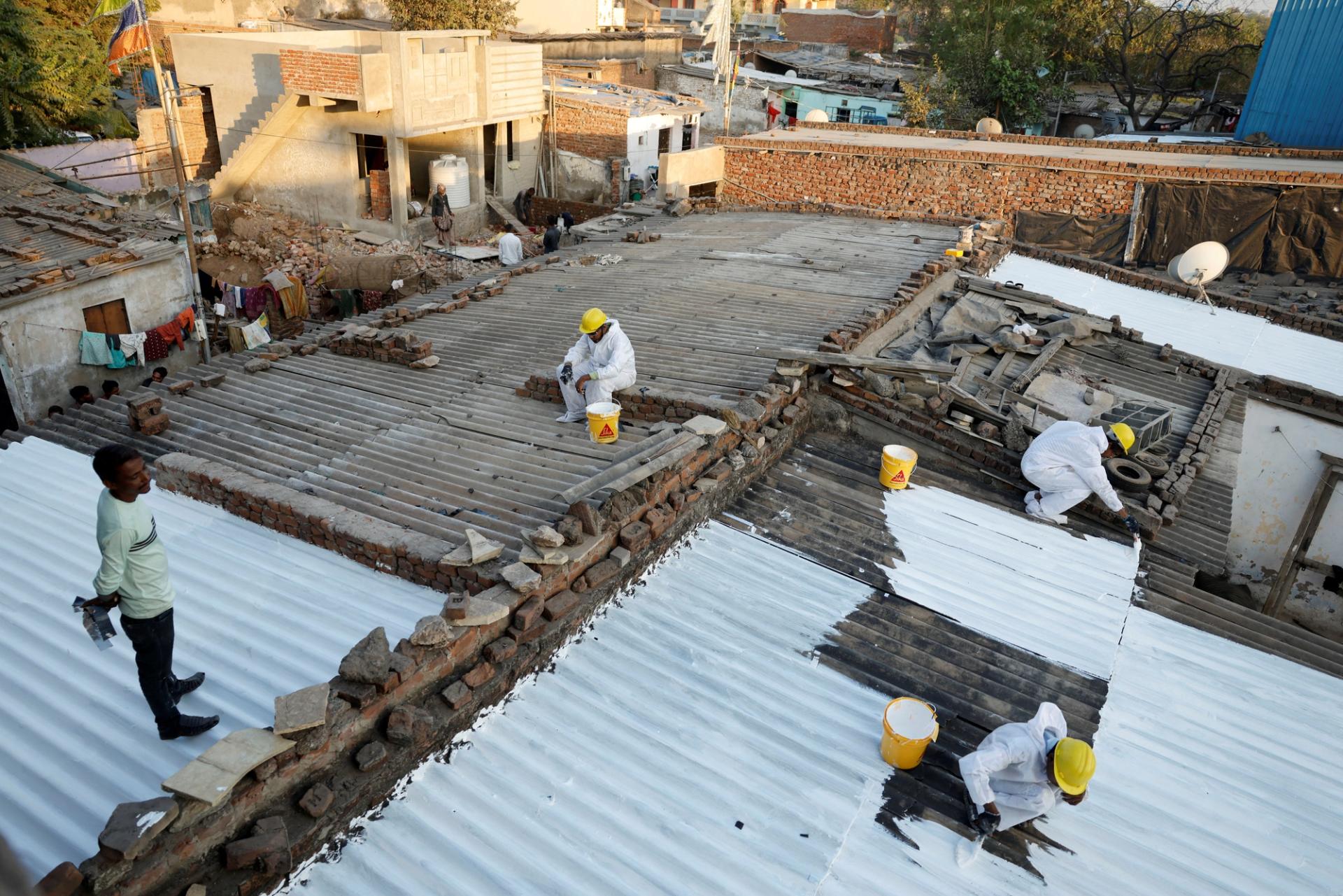 Painters apply liquid-applied membrane (LAM) coating that according to the authorities helps to bring down the temperature inside the shanties at a slum in Ahmedabad, India.