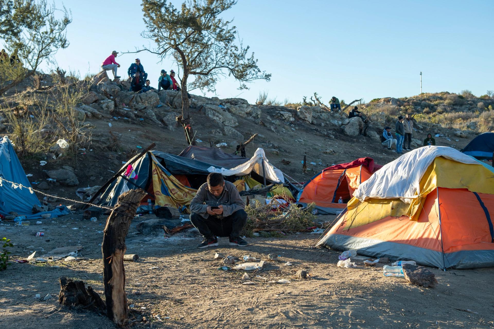 A Chinese migrant sit in front of his tent near the U.S.-Mexico border fence in Jacumba, Calif., on Dec, 6, 2023.