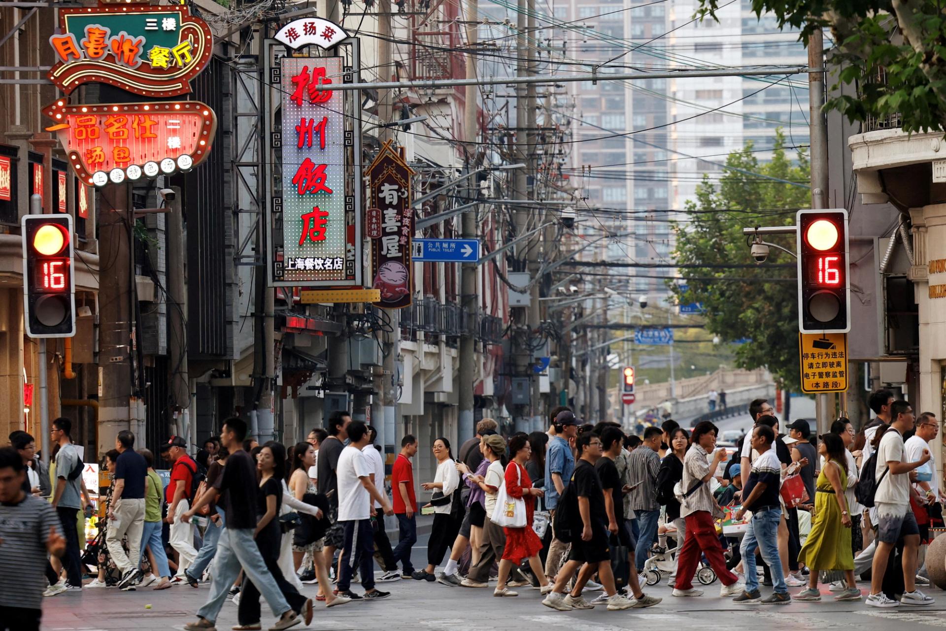 People walk past a lane lined up with restaurants, at a shopping area in Shanghai.