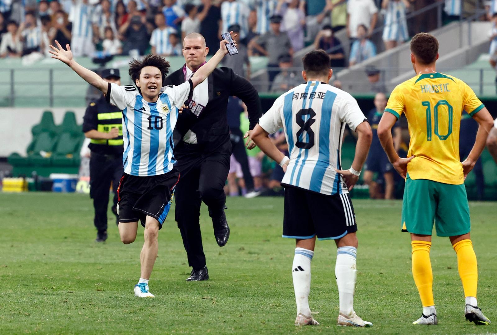 A pitch invader is chased by security officials during the match.
