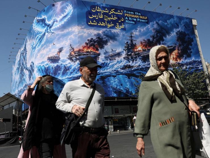 People walk past a billboard about the Strait of Hormuz in Tehan, Iran.