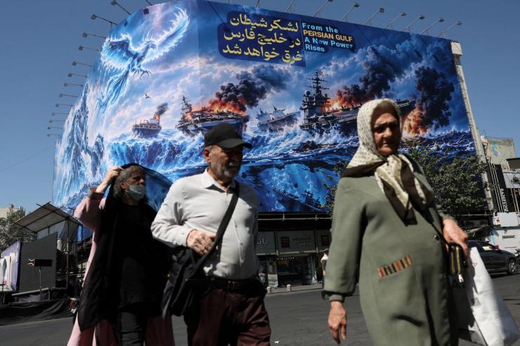 People walk past a billboard about the Strait of Hormuz in Tehan, Iran.