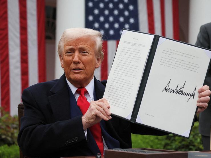 Donald Trump holds a signed executive order on tariffs in the Rose Garden of the White House.