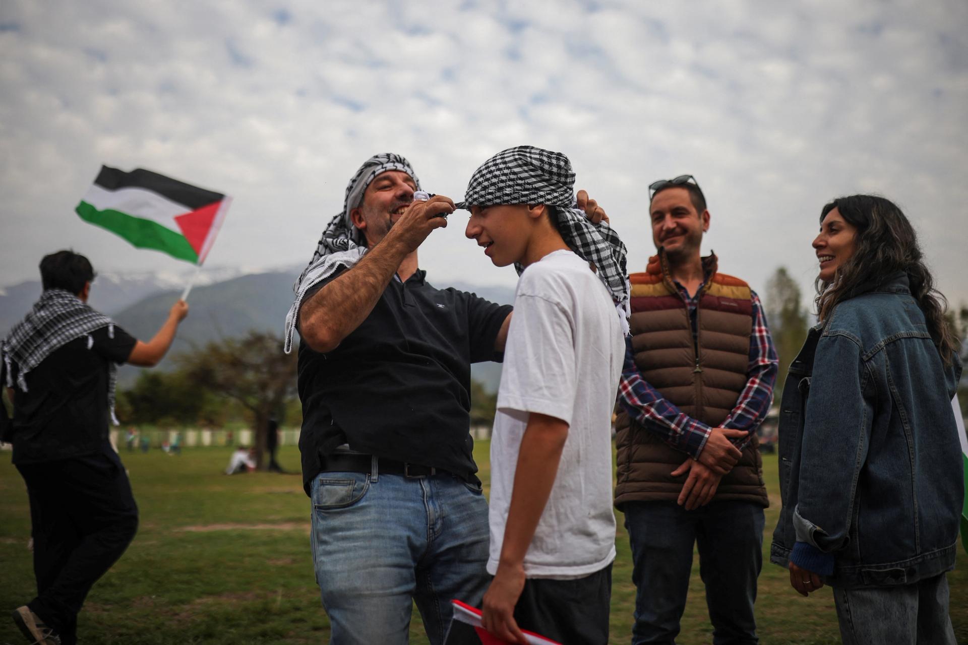A pro-Palestinian activist helps a man put on a Palestinian keffiyeh before a charity concert to fund hospitals in Gaza and West Bank, in Santiago, Chile October 25, 2023. 