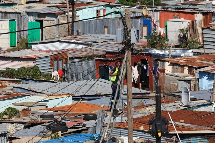 A worker works on an electricity pole in the Barcelona informal settlement in Cape Town.
