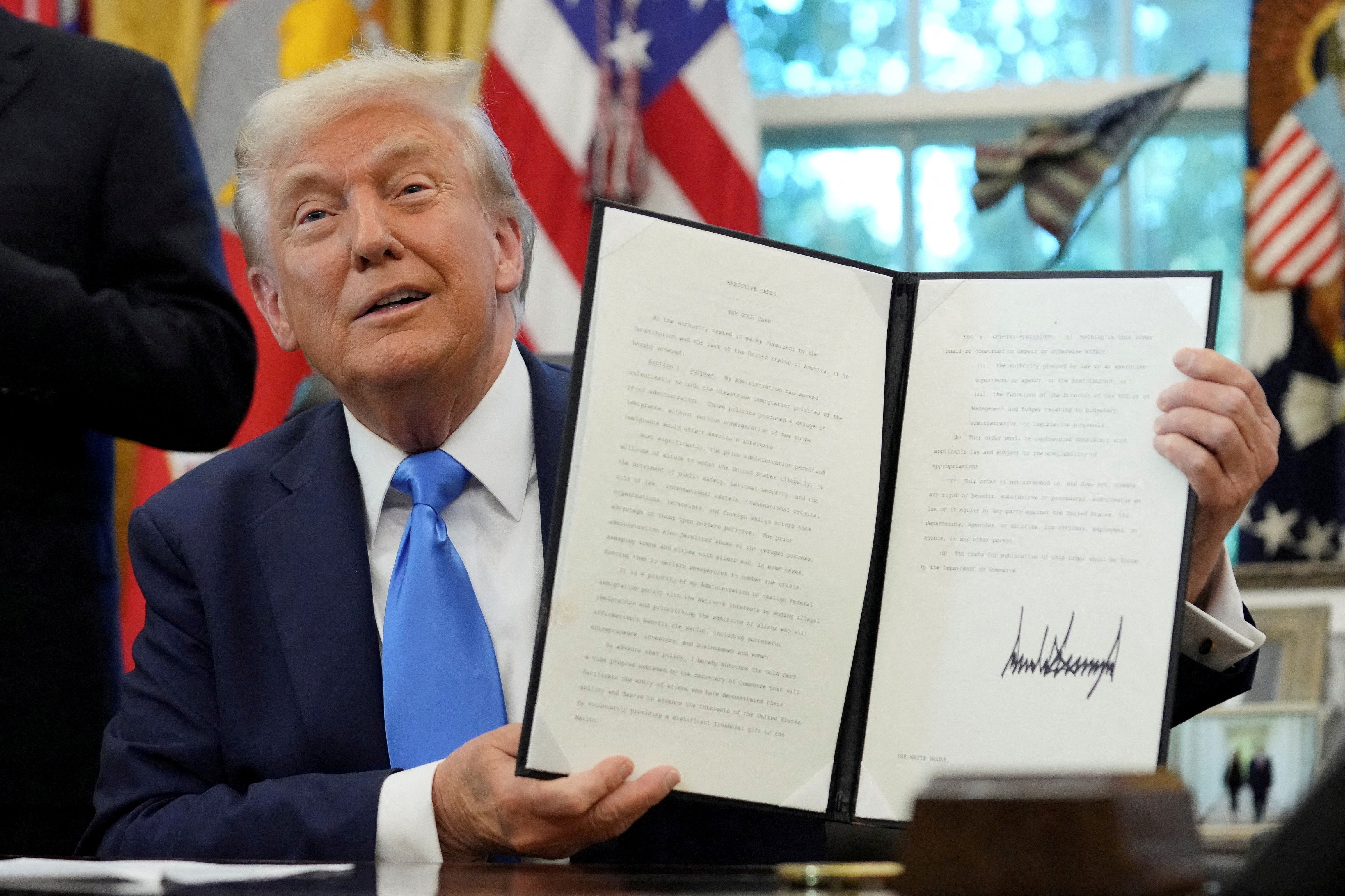U.S. President Donald Trump displays a signed executive order on gold card visa in the Oval Office