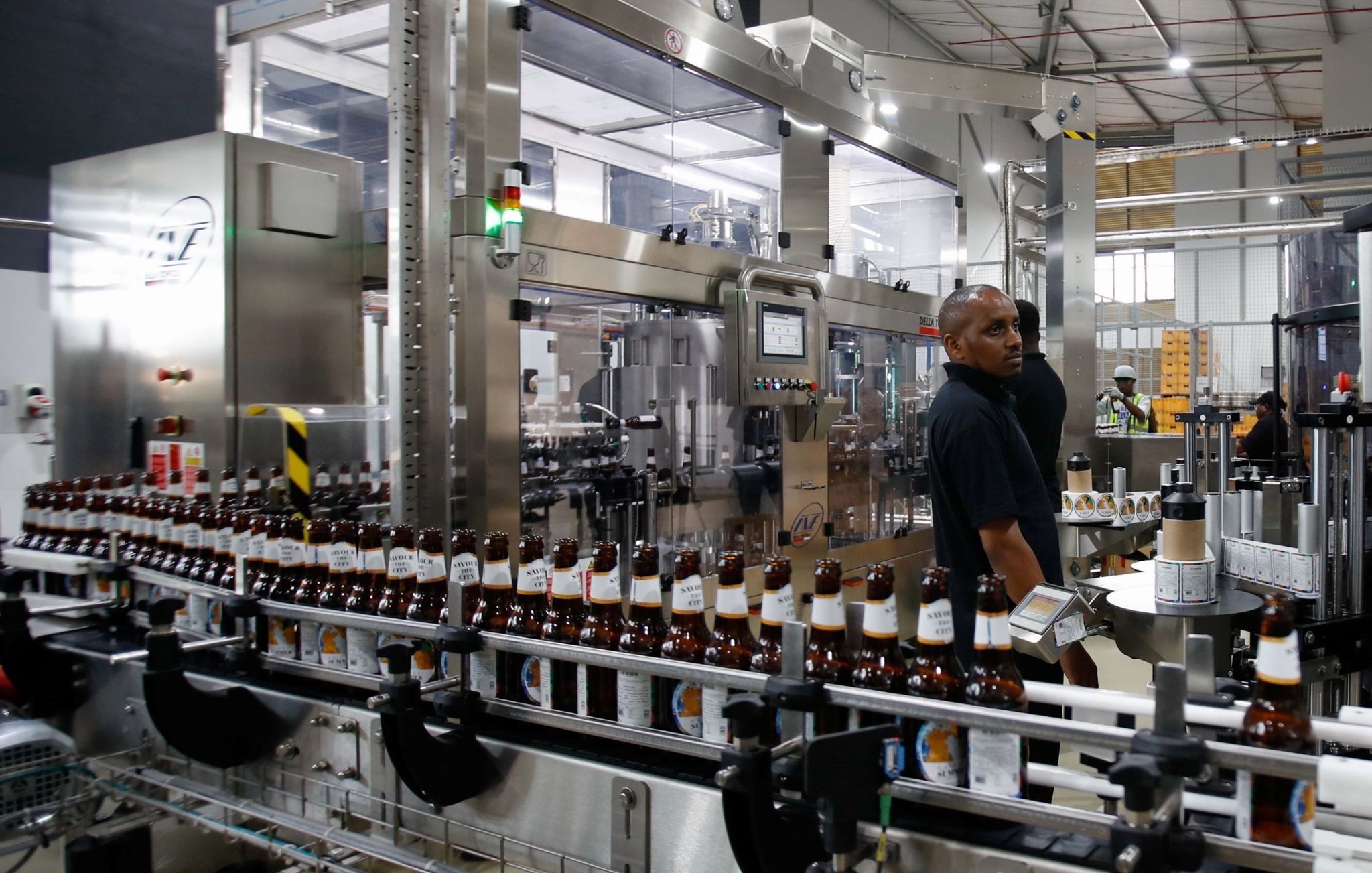 An employee inspects beer bottles on a conveyor belt along a production line at the East African Breweries’ microbrewery in Nairobi, Kenya. 