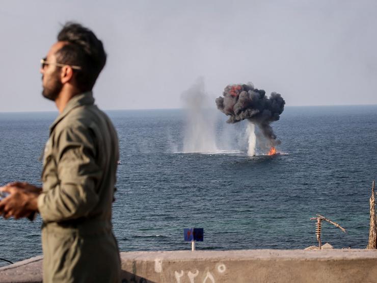 An explosion is seen behind a member of the Islamic Revolution Guards Corps during a joint military exercise called the ‘Great Prophet 17’ in the southwest of Iran, in this picture obtained on Dec. 22, 2021.