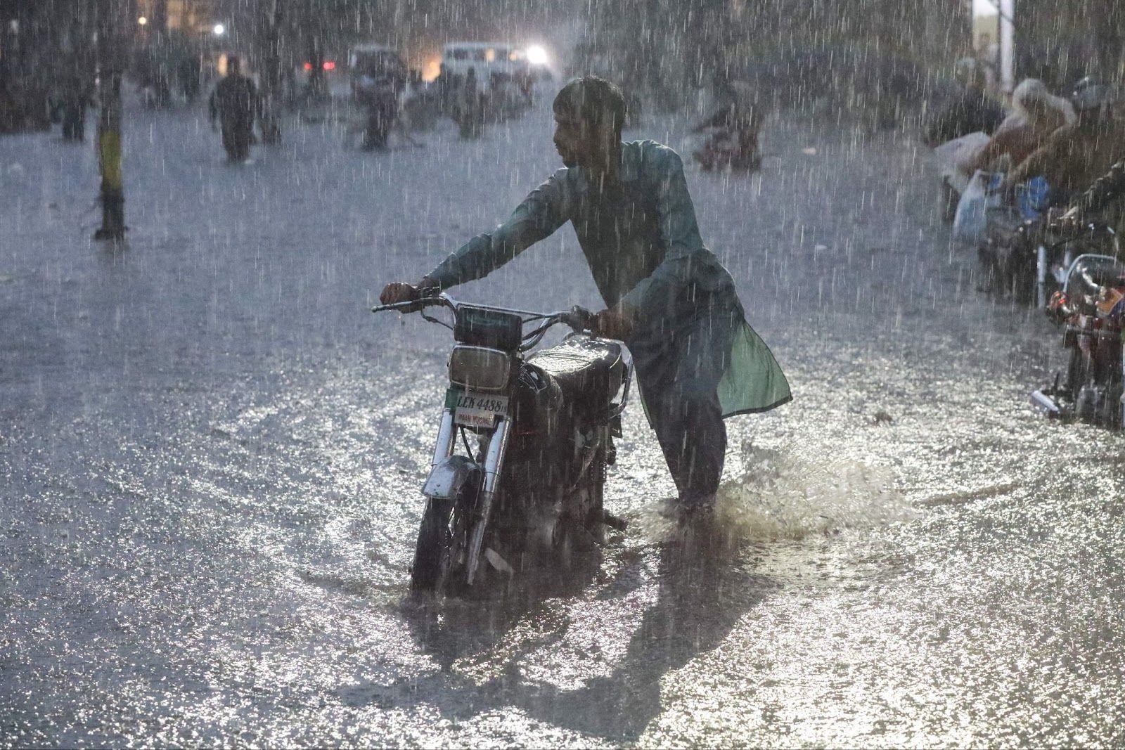 A man pushing a motorcycle in a flood in Lahore.