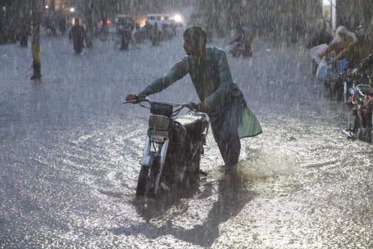 A man pushing a motorcycle in a flood in Lahore.