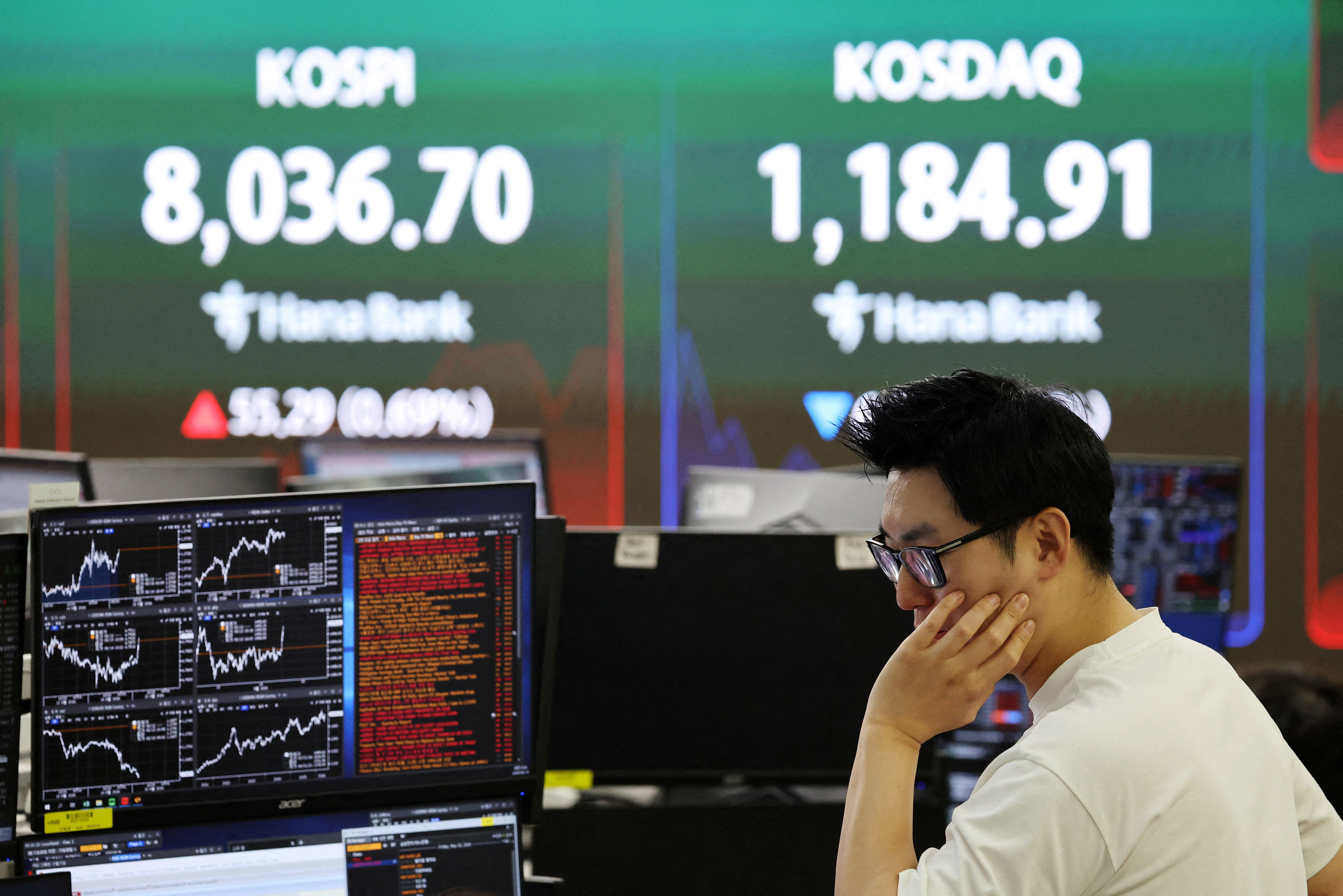 A currency dealer works as an electronic board displays the Korea Composite Stock Price Index (KOSPI) and the Korea Securities Dealers Automated Quotations (KOSDAQ).