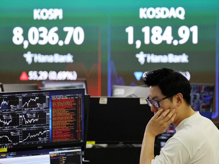 A currency dealer works as an electronic board displays the Korea Composite Stock Price Index (KOSPI) and the Korea Securities Dealers Automated Quotations (KOSDAQ).