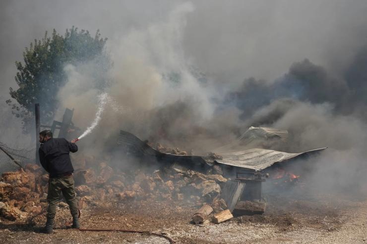 A man tries to extinguish a burning house during a wildfire in Nea Penteli, Greece in August.