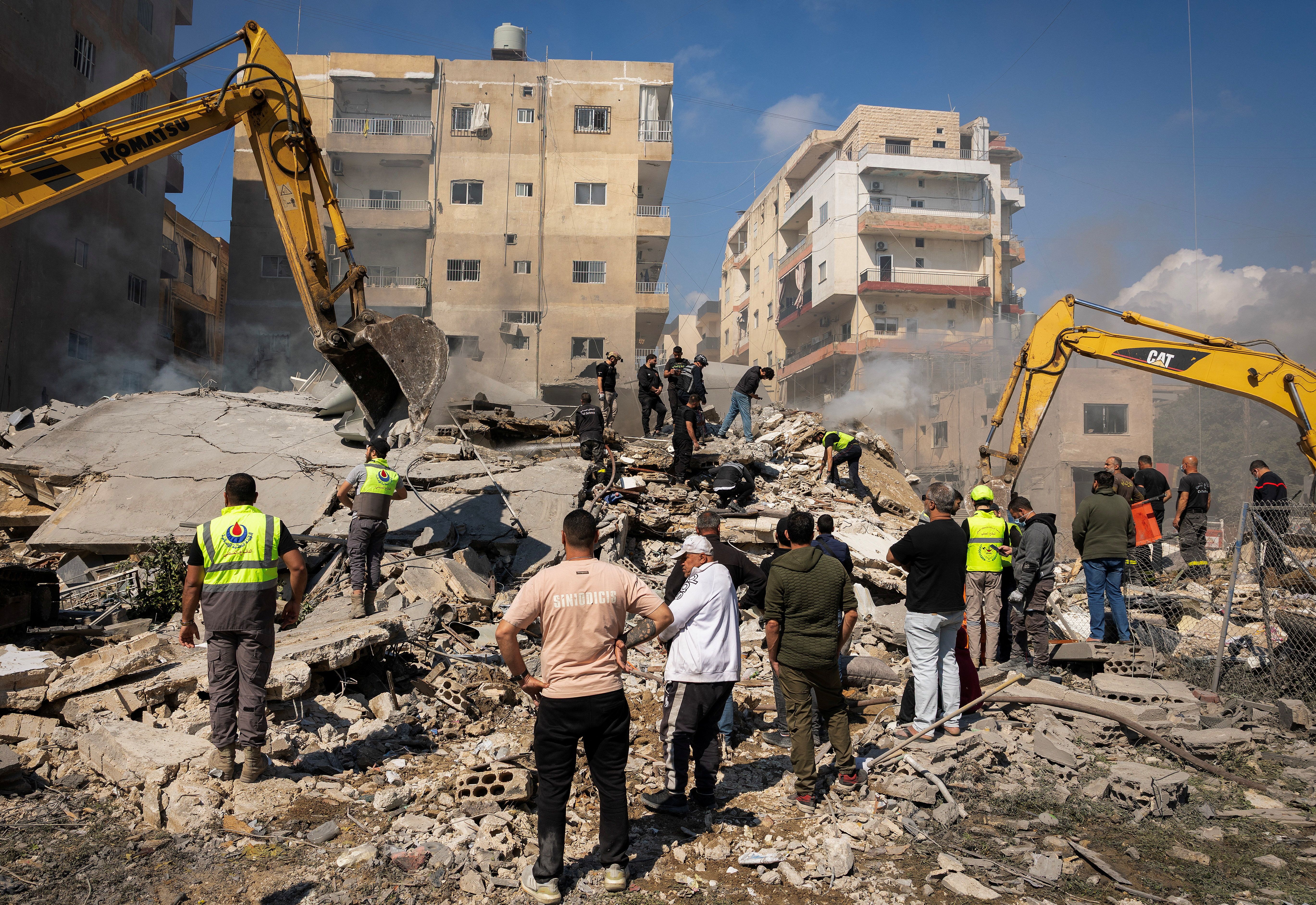 Rescuers stand amid rubble at the site of an Israeli strike in Tyre, Lebanon