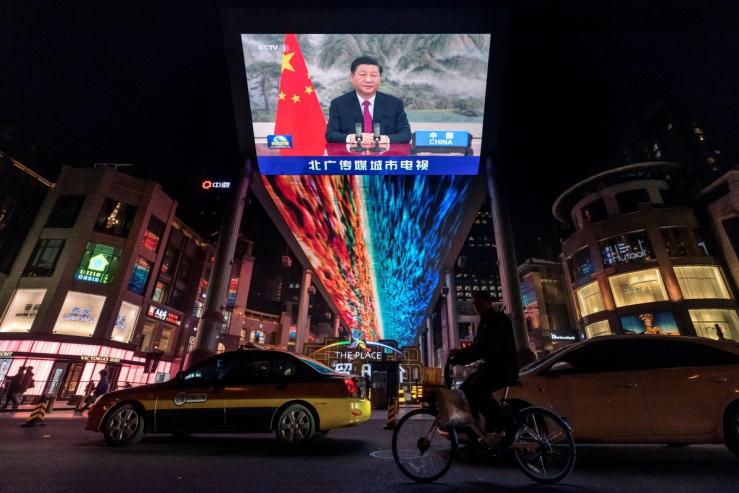 A screen displays a CCTV state media news broadcast showing Chinese President Xi Jinping.